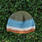Crocheted beanie with striped colors on grass.
