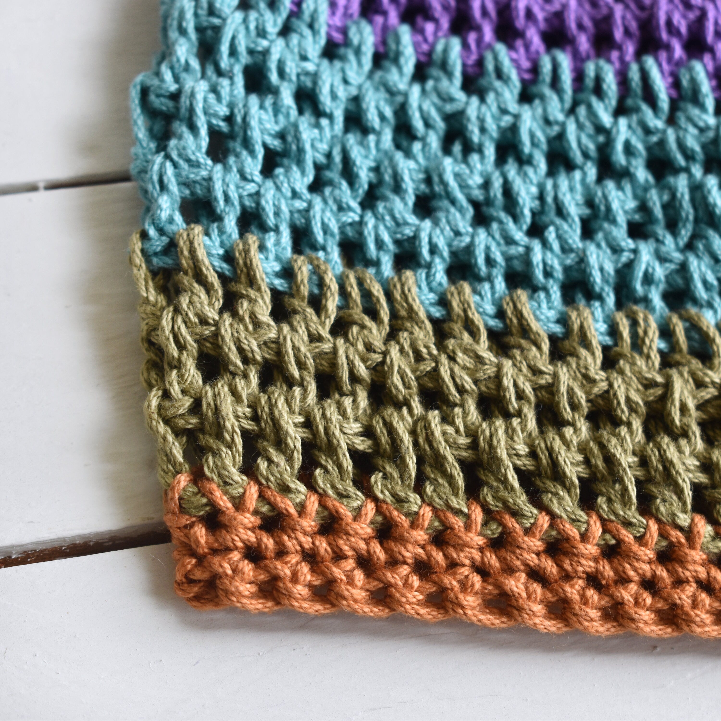 Close-up of a crocheted hat with a striped pattern on a wooden surface.