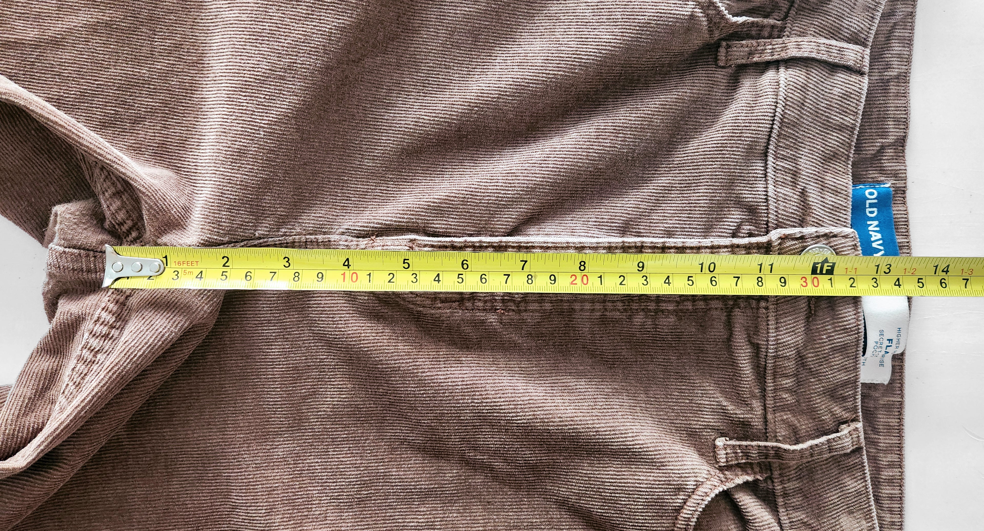 Brown corduroy pants with a measuring tape running down the rise of the pants.