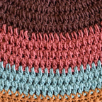 Close-up of a crocheted hat with a striped pattern in brown, pink, blue, and orange.