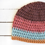 Multicolored crocheted beanie on a white wooden surface.