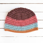 Multicolored crocheted beanie on a white wooden surface.