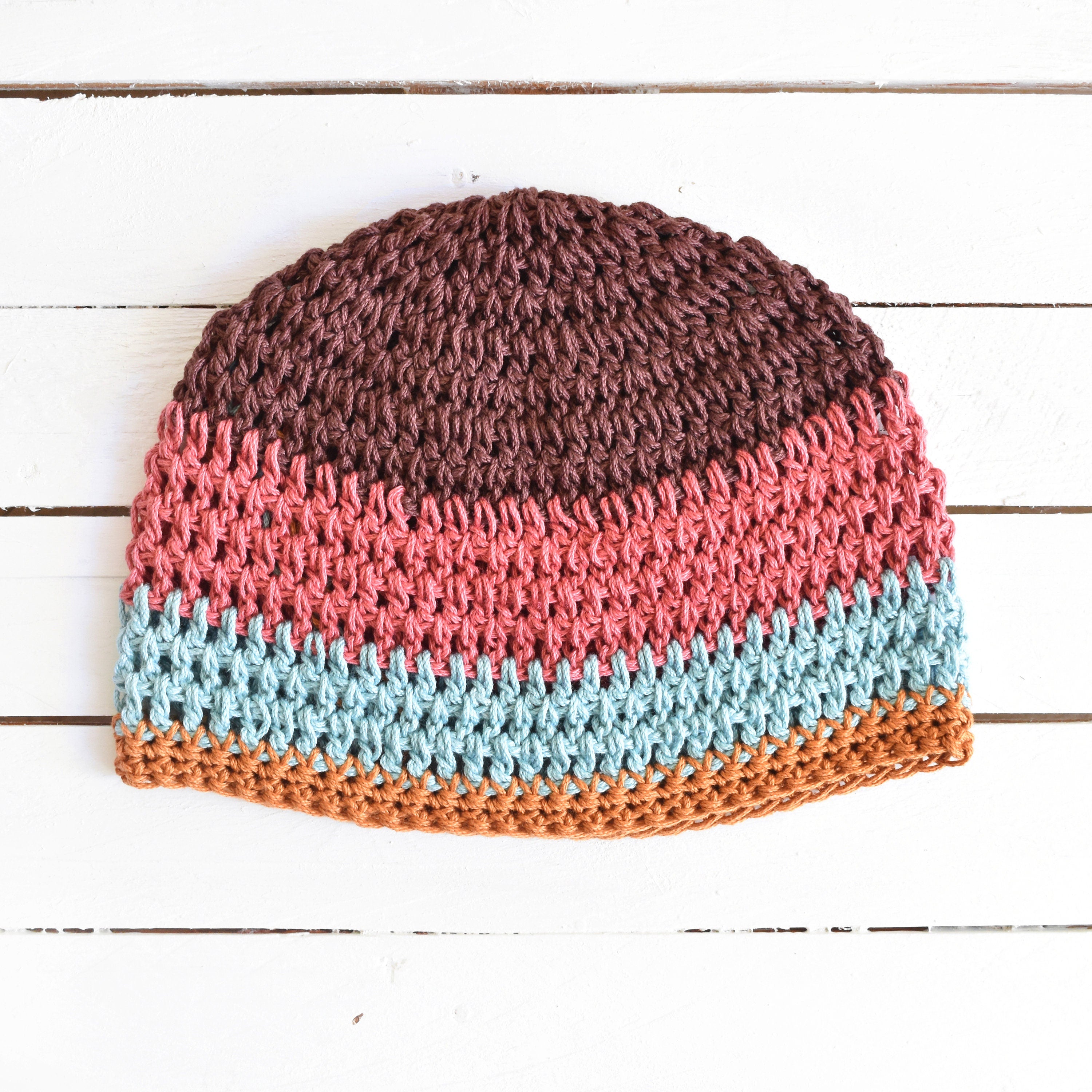 Multicolored crocheted beanie on a white wooden surface.