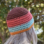 Colorful crocheted beanie worn by a person outdoors with a blurred natural background.