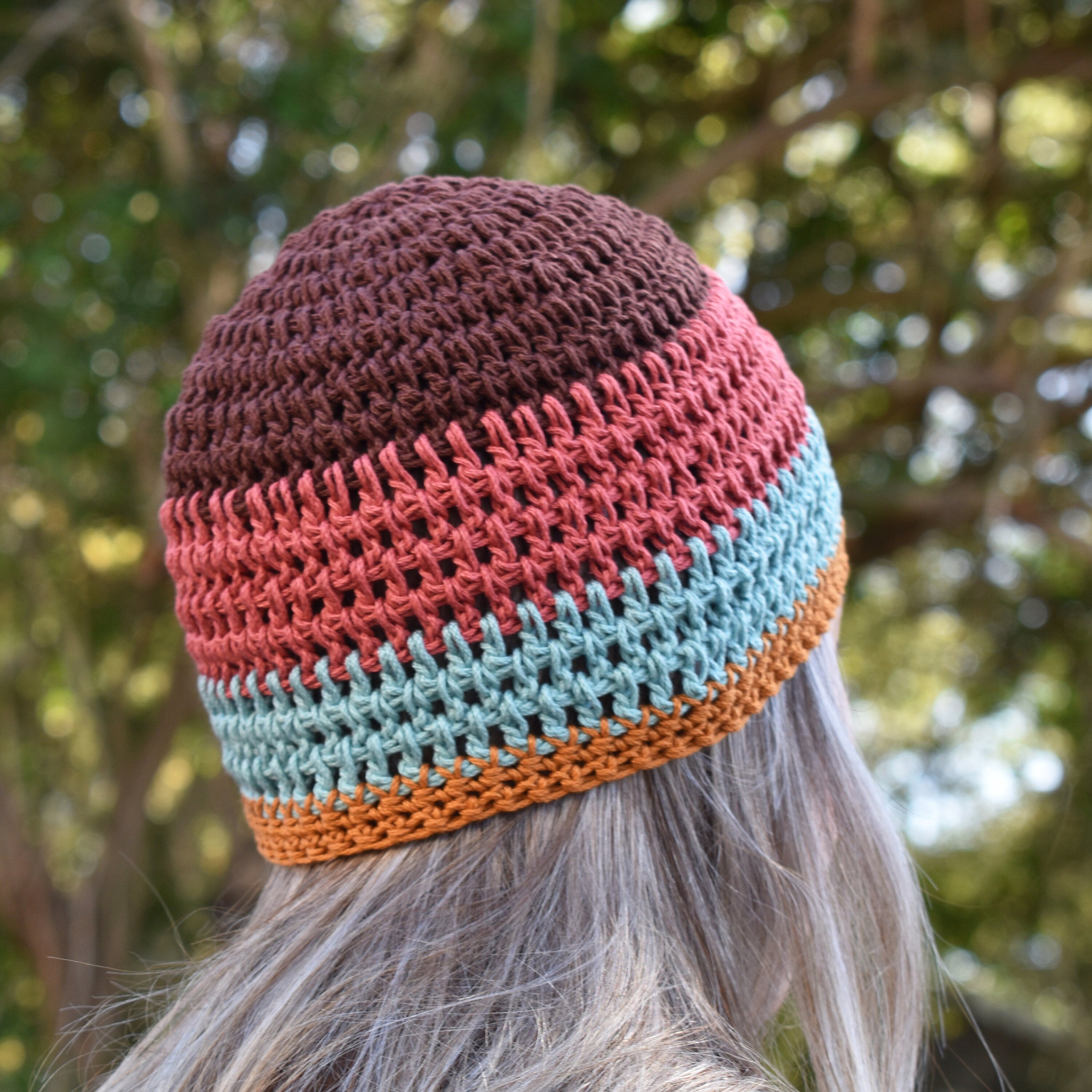 Colorful crocheted beanie worn by a person outdoors with a blurred natural background.