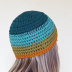 Colorful knitted beanie on a person with long hair against a neutral background.