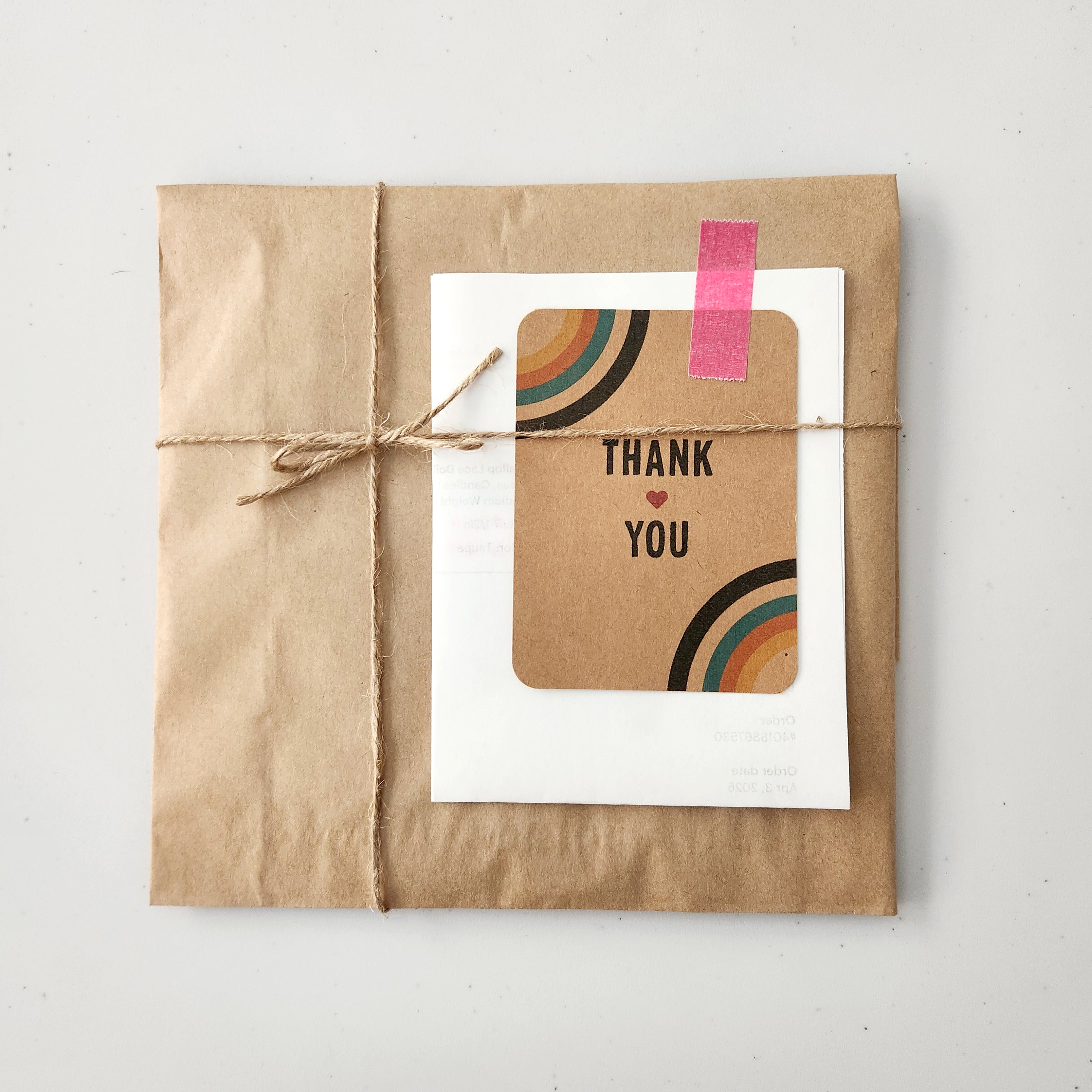 Kraft paper-wrapped package with a 'Thank You' card featuring rainbow design on a light gray background.