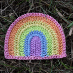 Crocheted rainbow patch with pastel colors on grass.