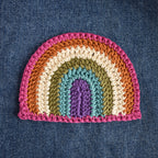 Crocheted rainbow patch on denim fabric.