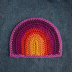 Crocheted rainbow patch on denim fabric.