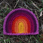 Crocheted rainbow patch on grass.