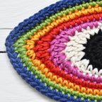 Close-up view of a colorful crocheted appliqué on a white wooden surface.