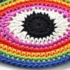Close-up view of a crocheted eye-shaped patch in rainbow colors.