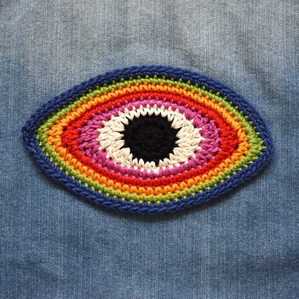 Colorful crocheted eye patch on denim fabric.