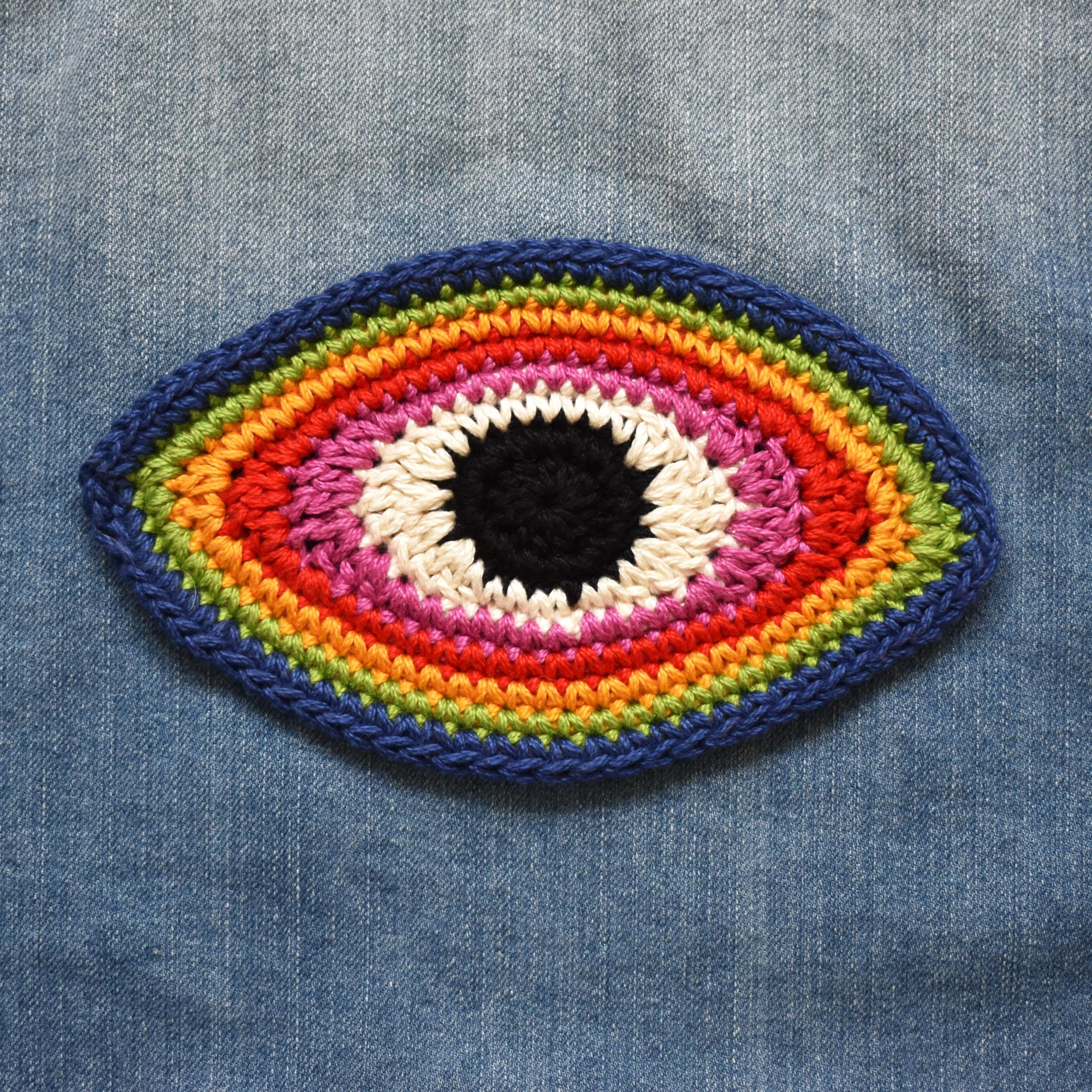 Colorful crocheted eye patch on denim fabric.