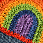 Close-up of a colorful crocheted patch on denim fabric.