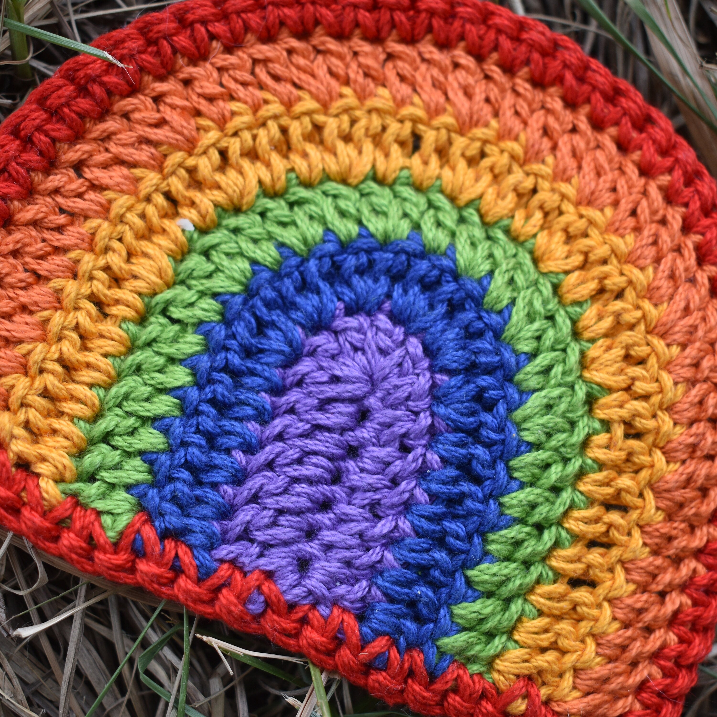 Close-up of a colorful crocheted rainbow on a natural background.