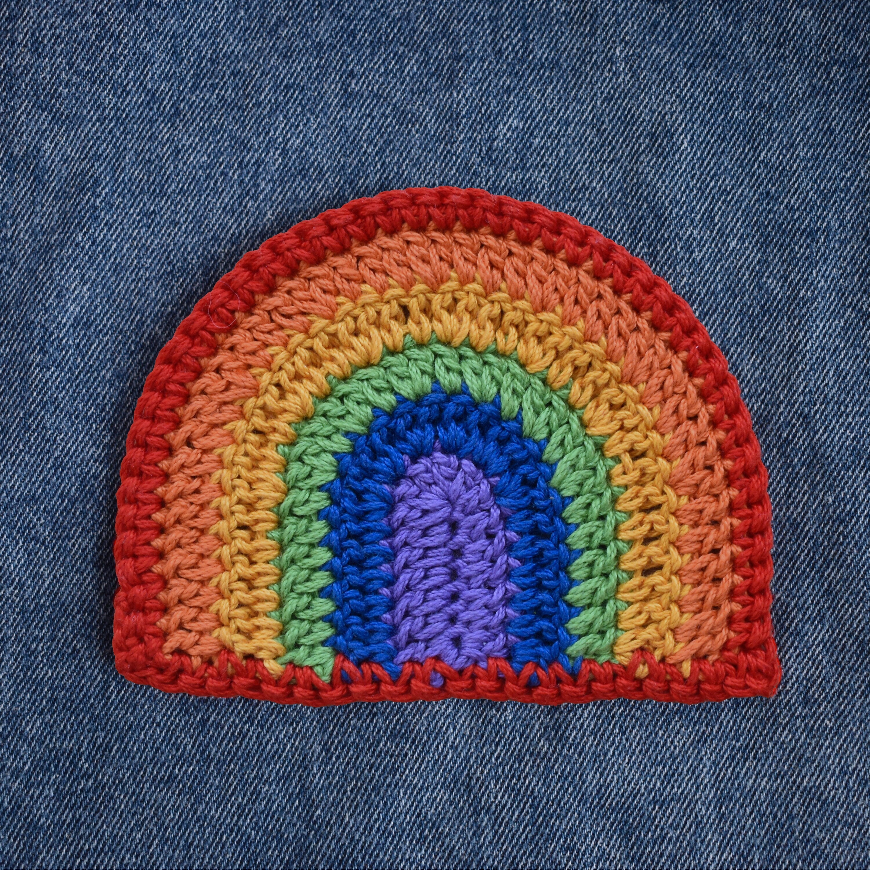 Crocheted rainbow patch on denim fabric.