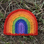 Crocheted rainbow patch on grass.