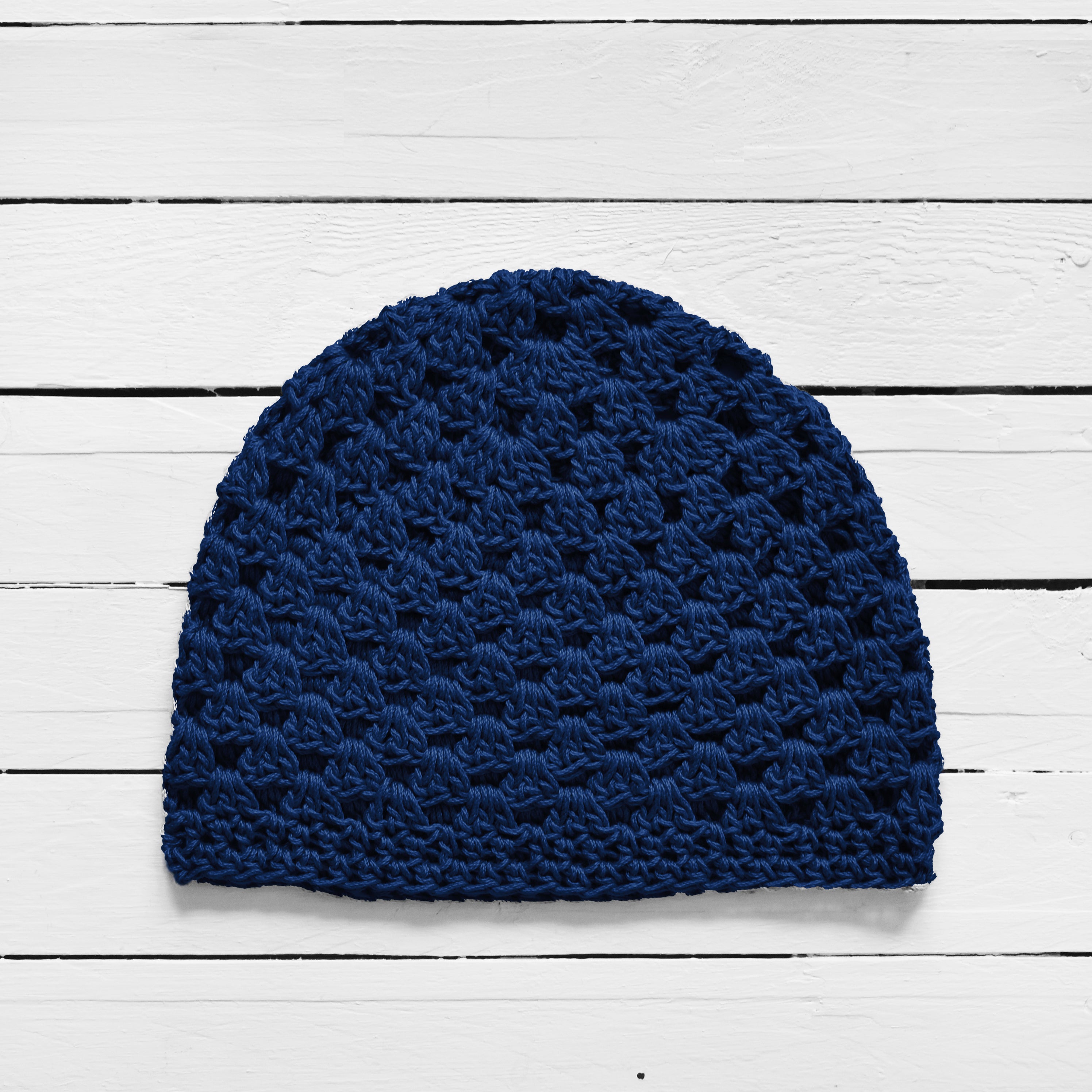 Navy blue knitted beanie on a white wooden surface.