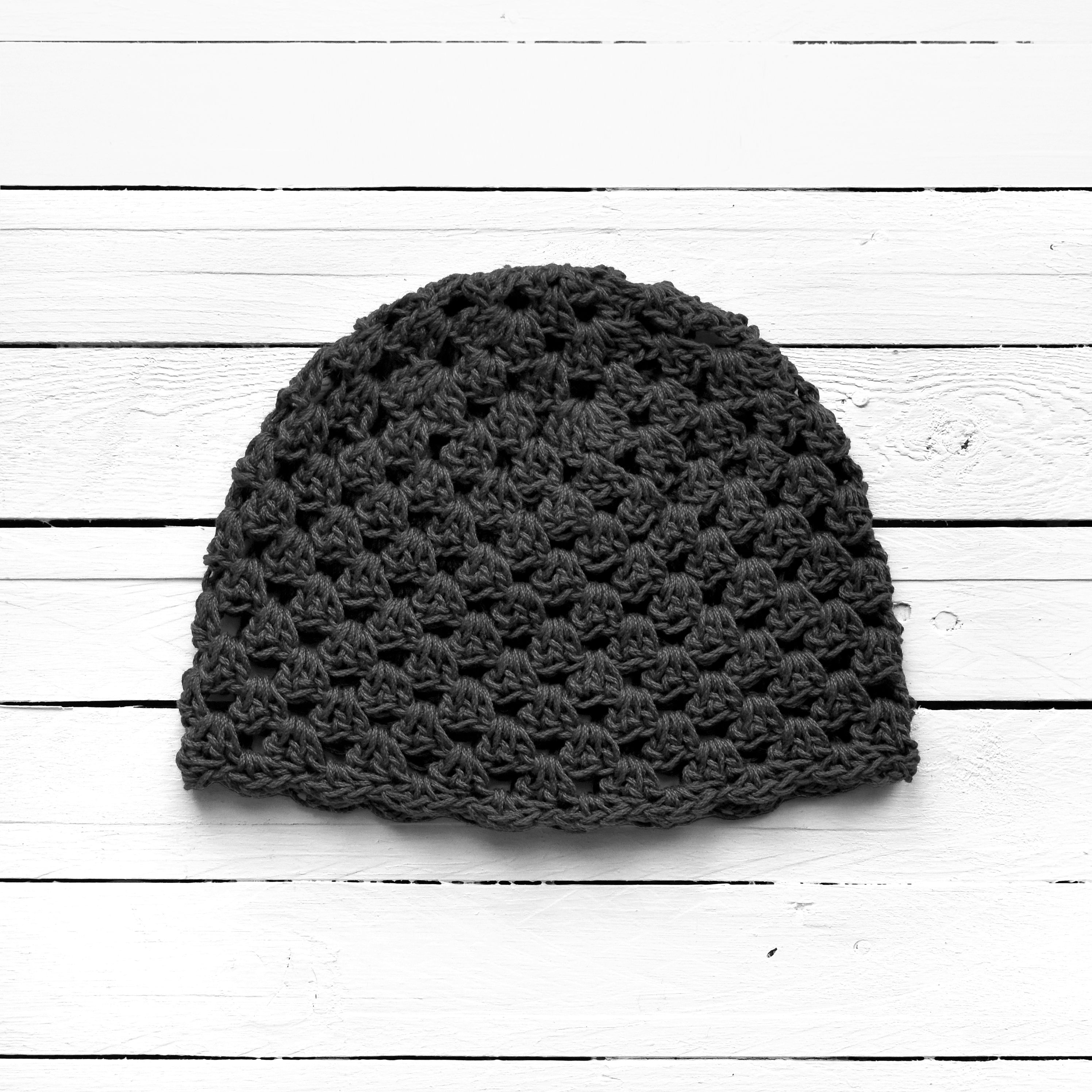 Dark gray crochet beanie on a light wooden surface.