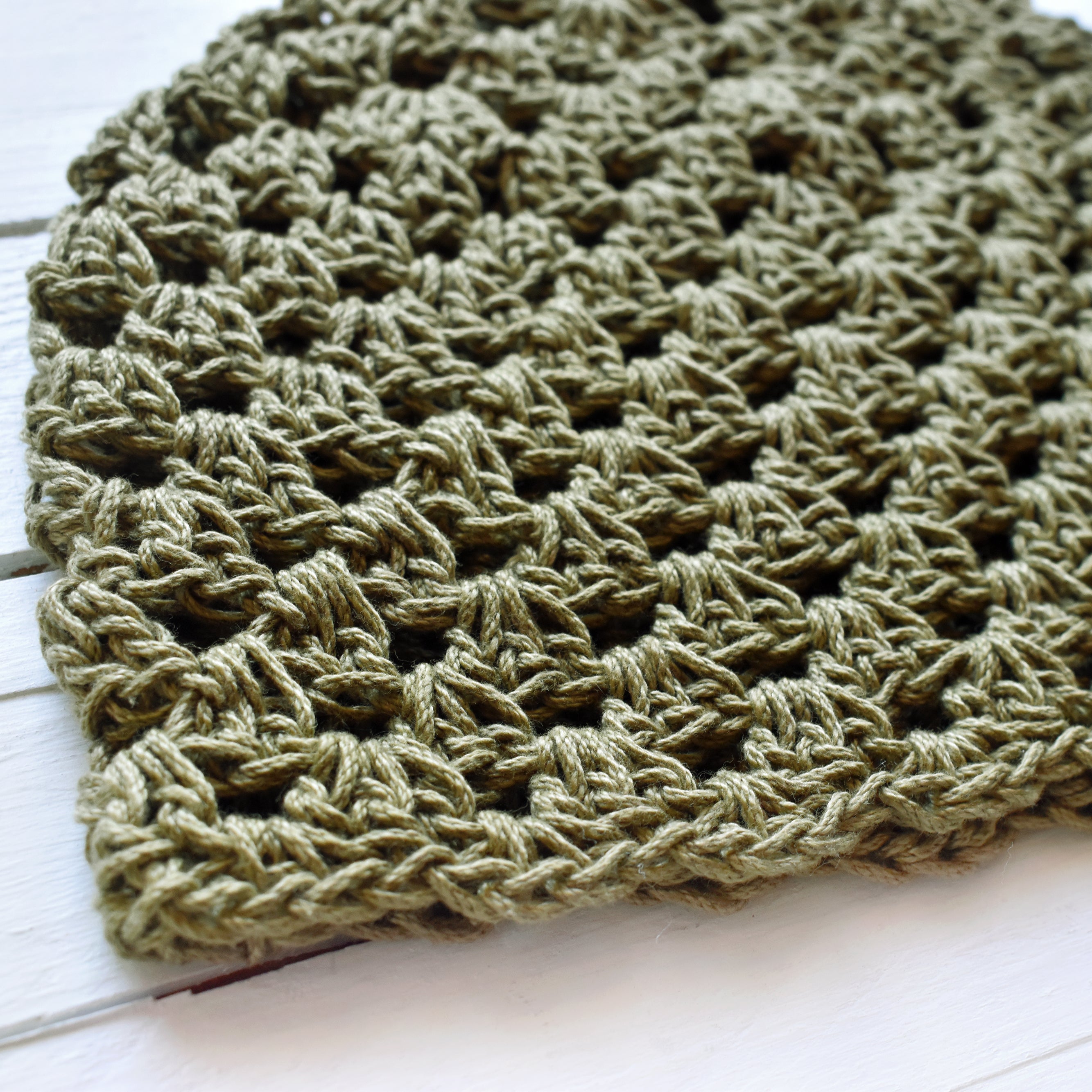 Close-up of a green crocheted hat on a white background.