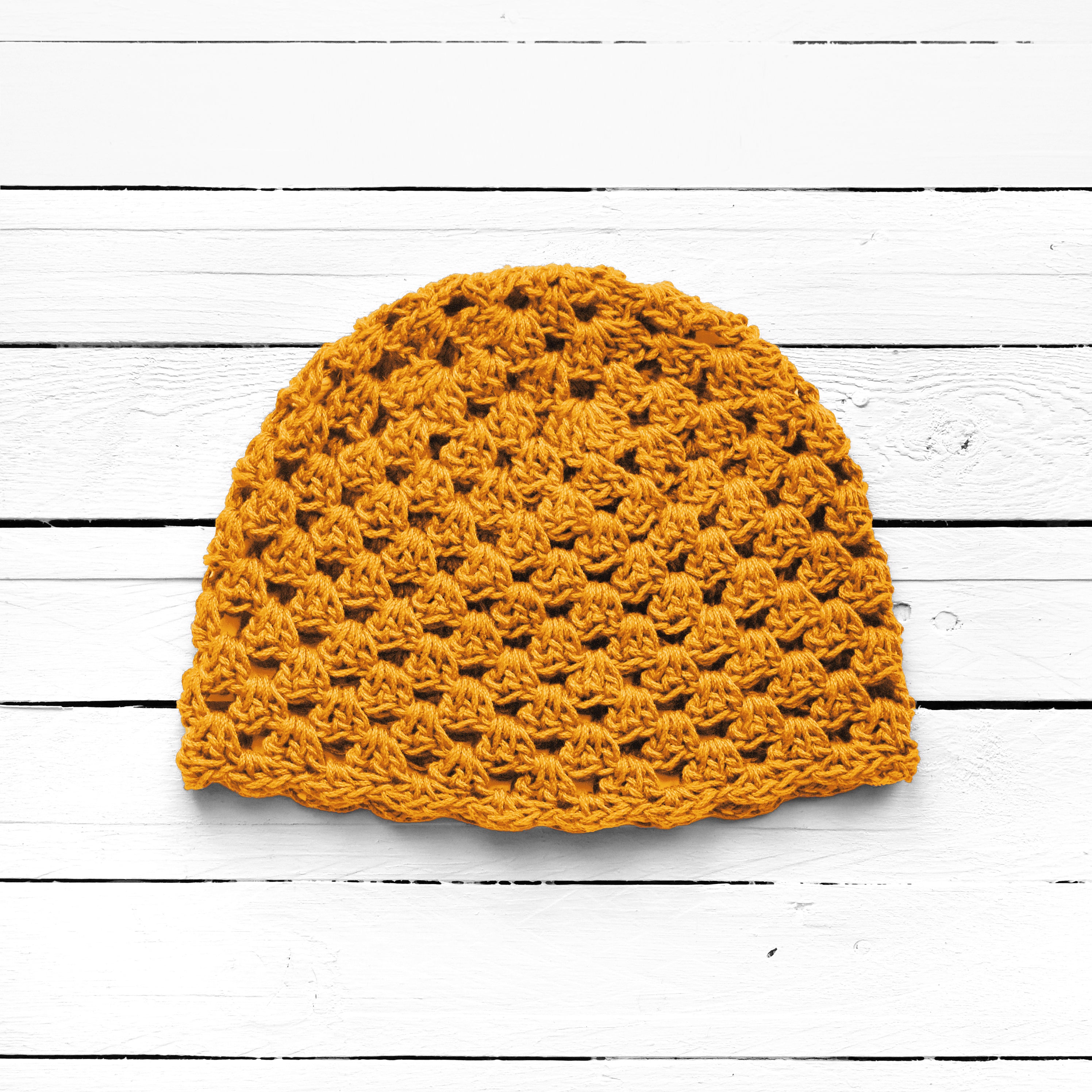 Yellow crochet beanie on a white wooden surface.