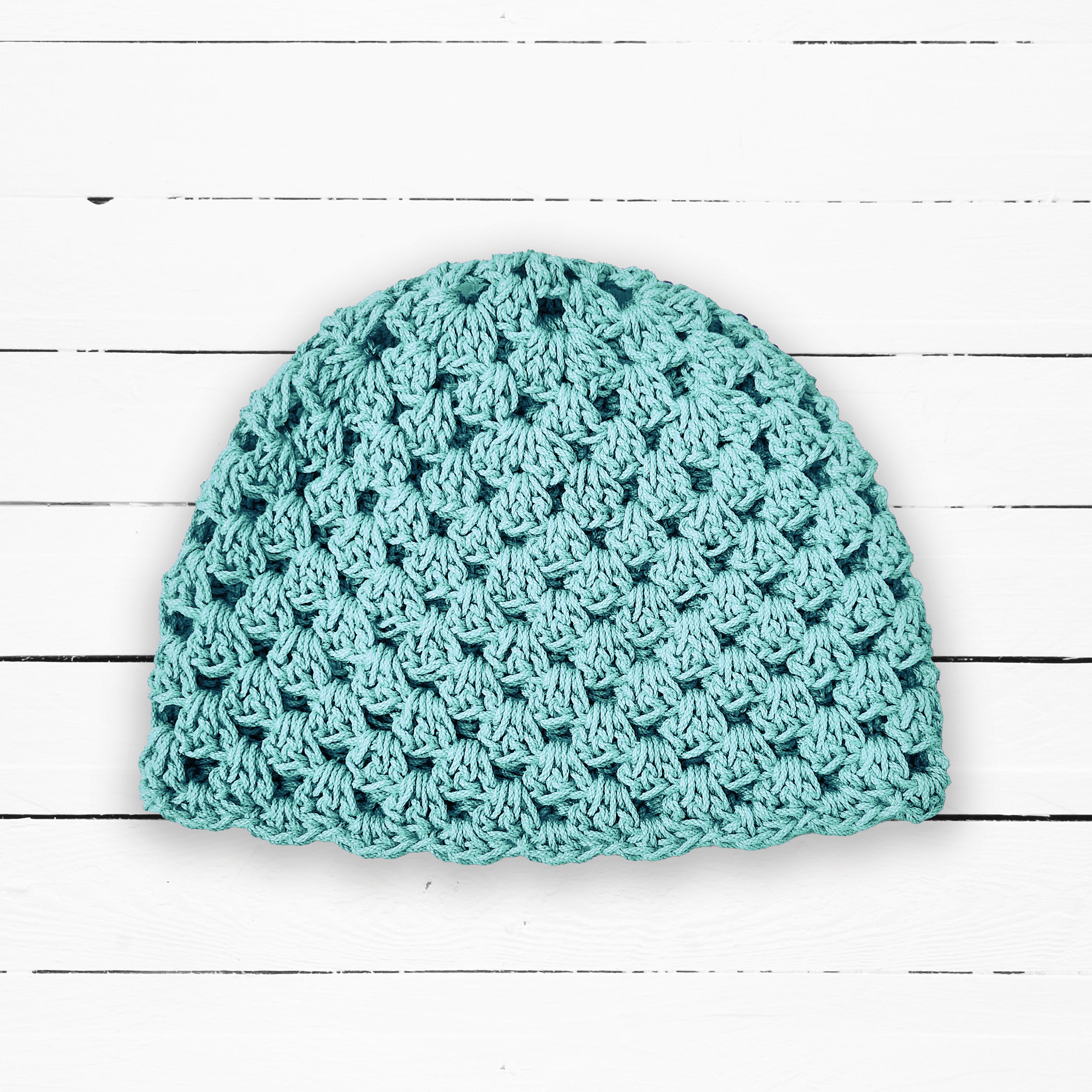 Light blue crochet beanie on a white wooden surface.