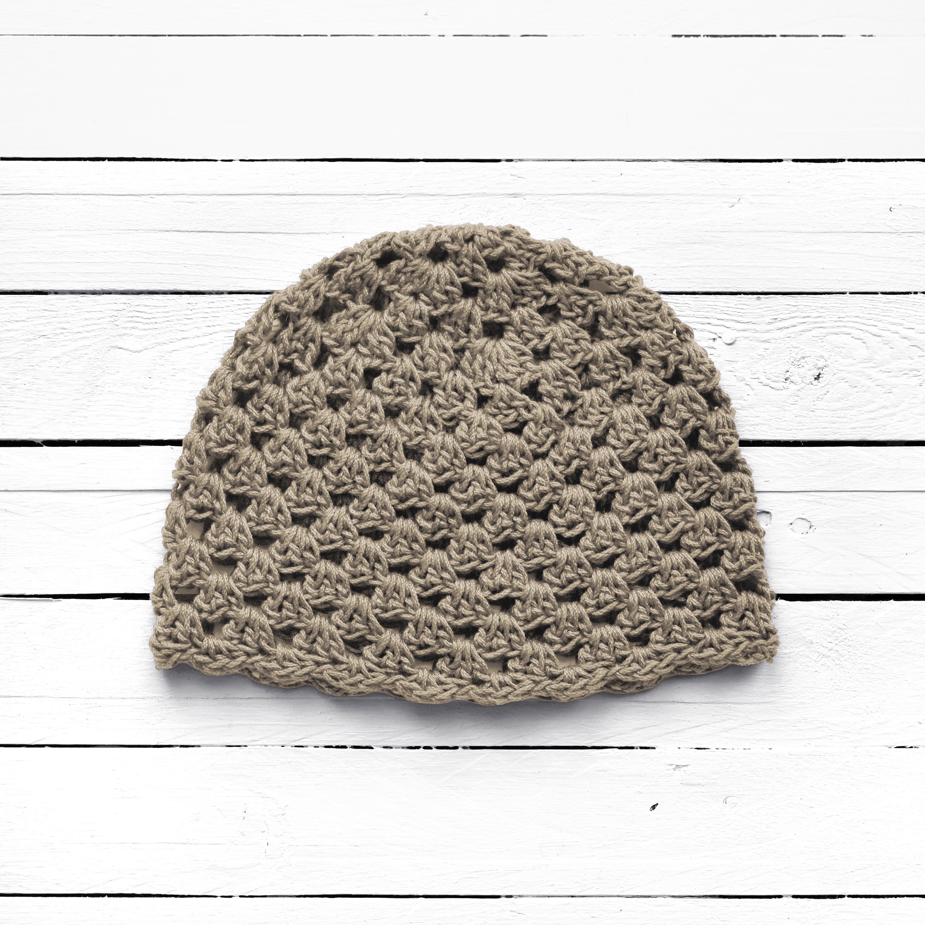 Taupe crocheted beanie on a white wooden surface.