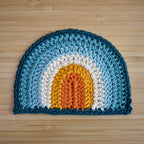 Crocheted rainbow with a colorful design on a wooden surface.