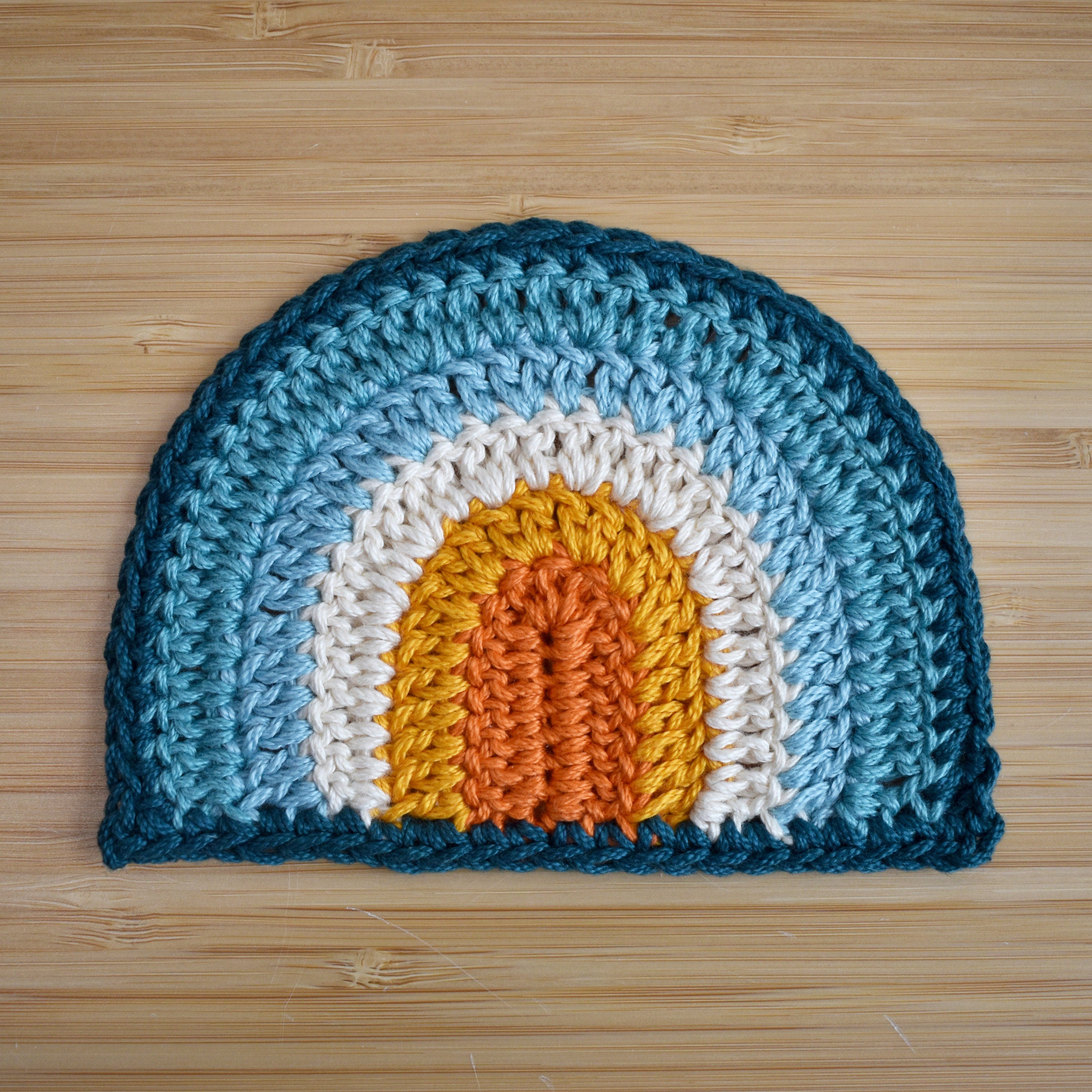 Crocheted rainbow with a colorful design on a wooden surface.