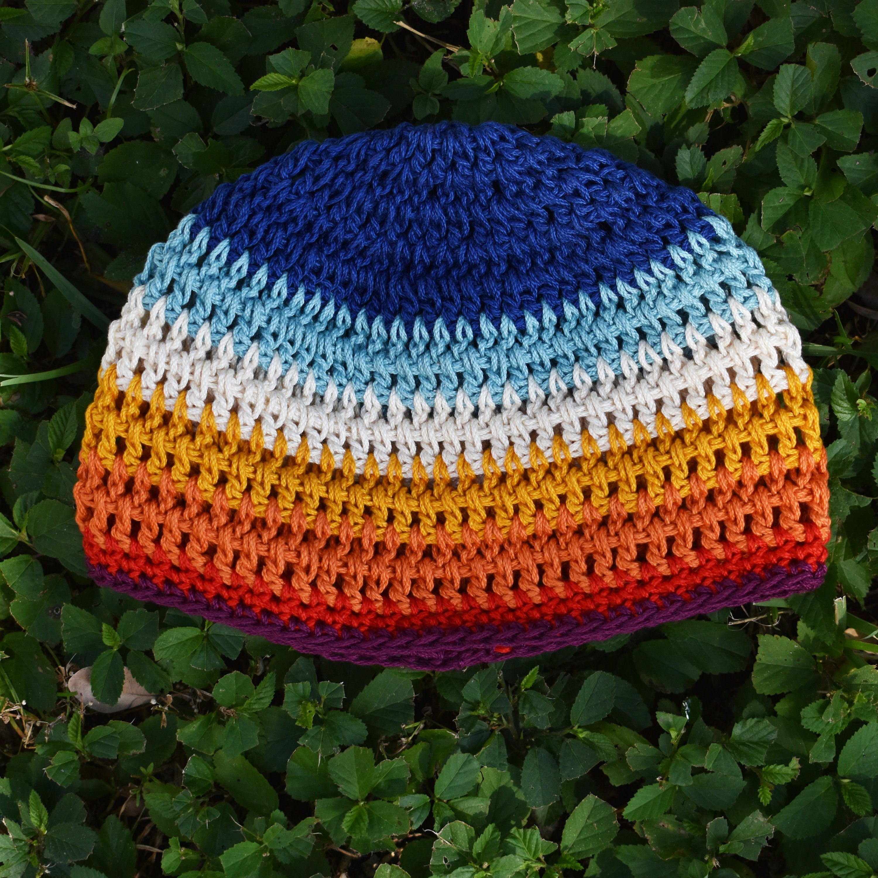 Colorful crocheted beanie with a striped pattern on the grass.