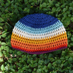 Colorful striped crocheted beanie on green grass.