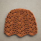 Amber orange crocheted lace beanie on a textured kraft background.