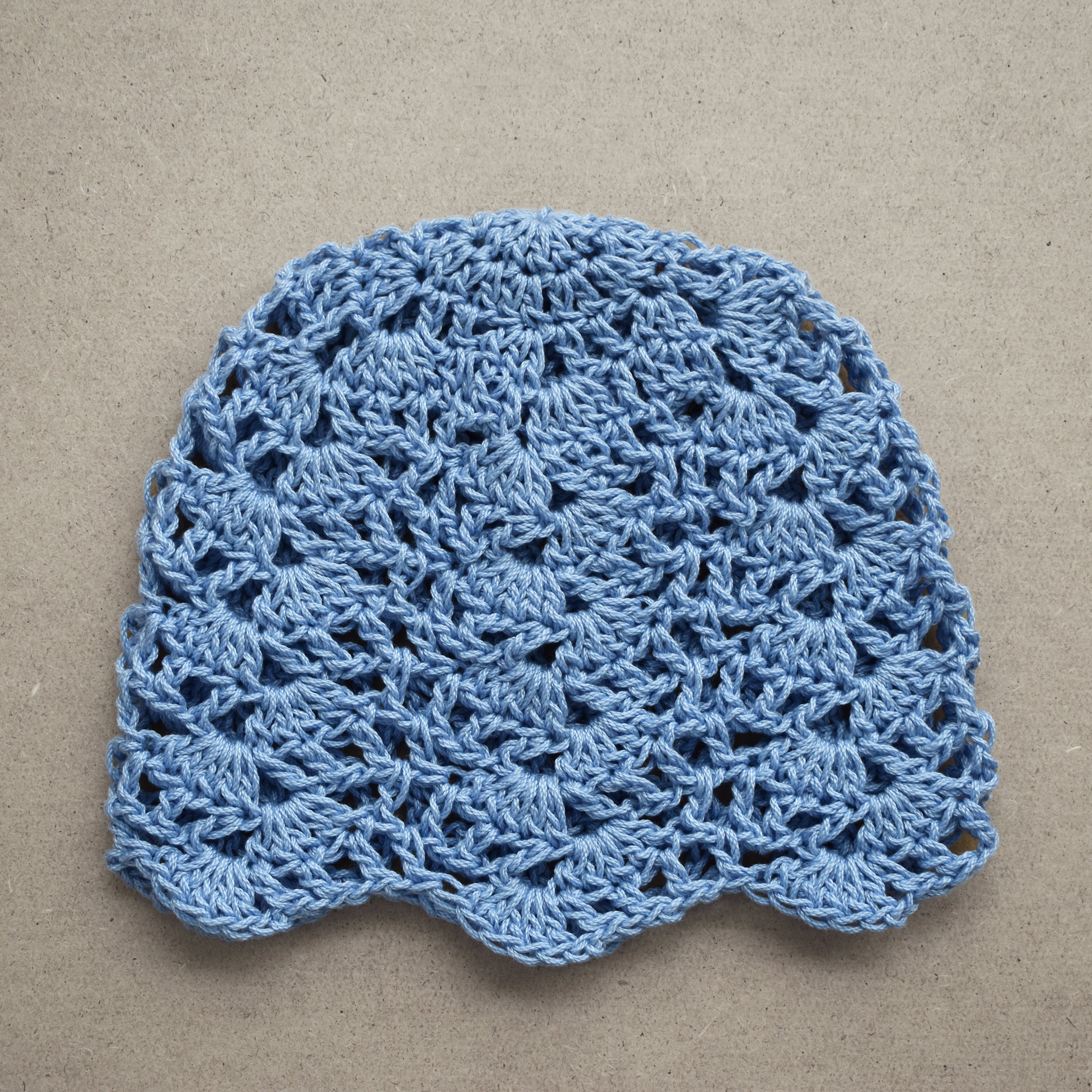 Baby blue crocheted hat on a beige background.