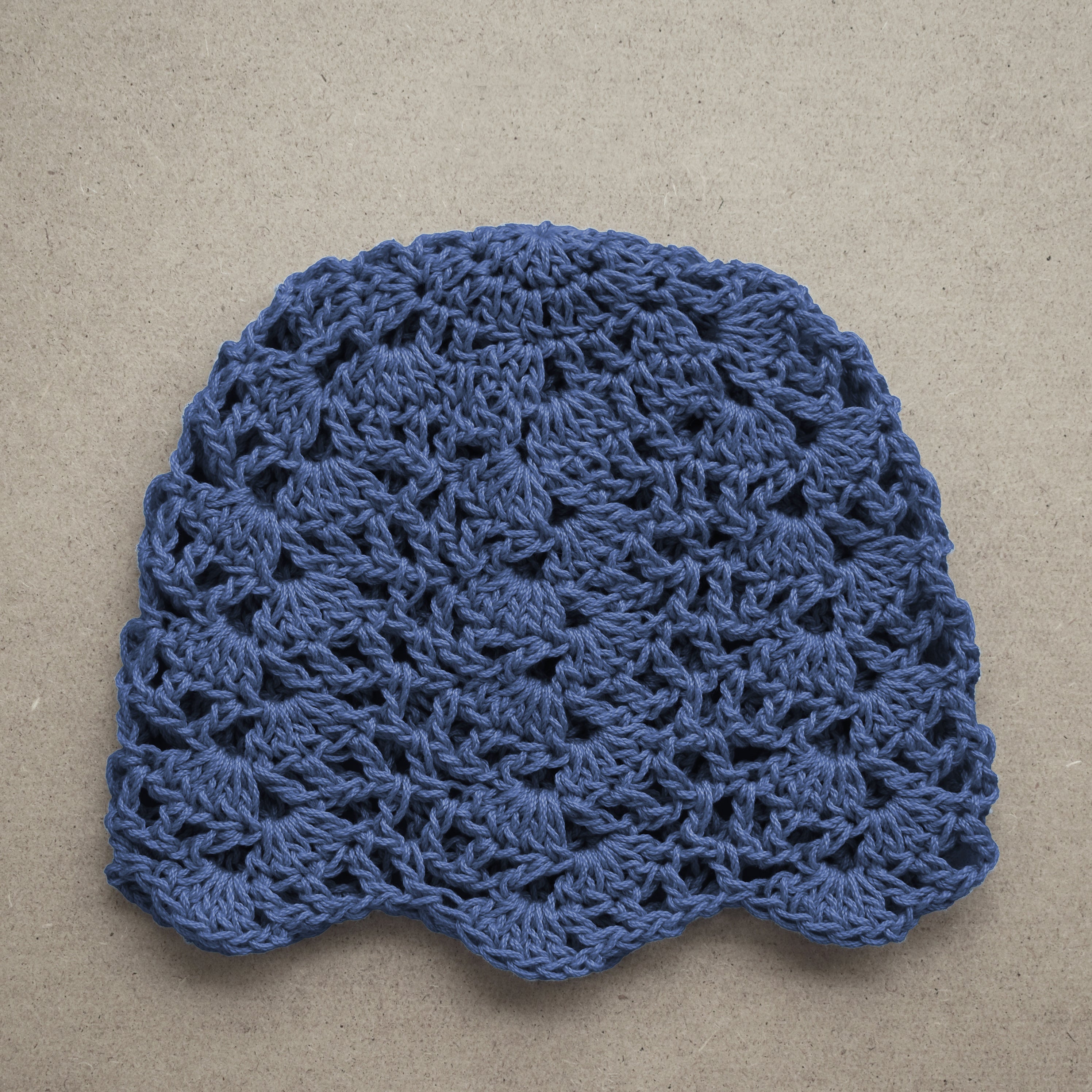 Blue crocheted hat on a beige background.