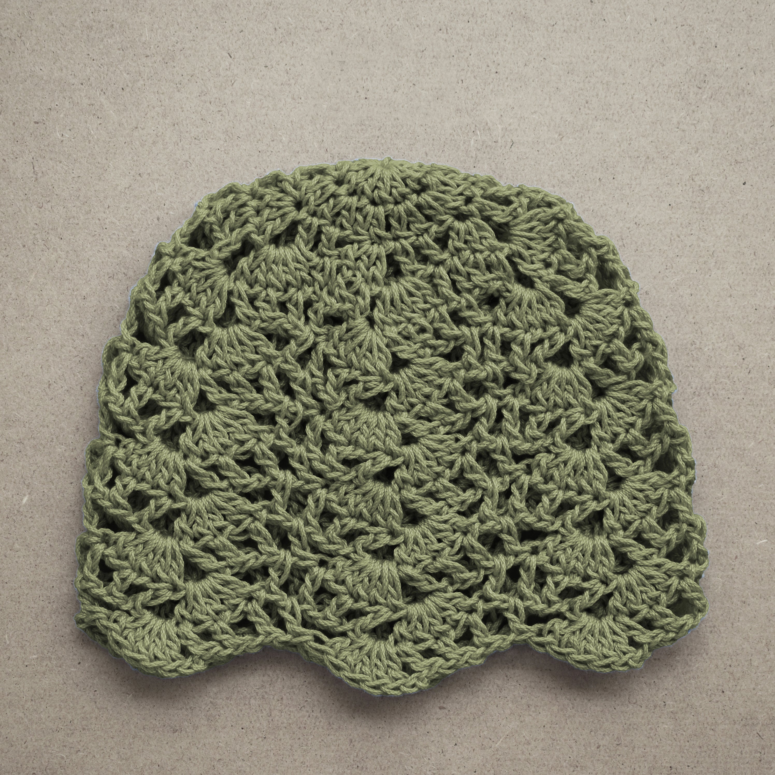 Sage green crocheted lace hat on a beige background.