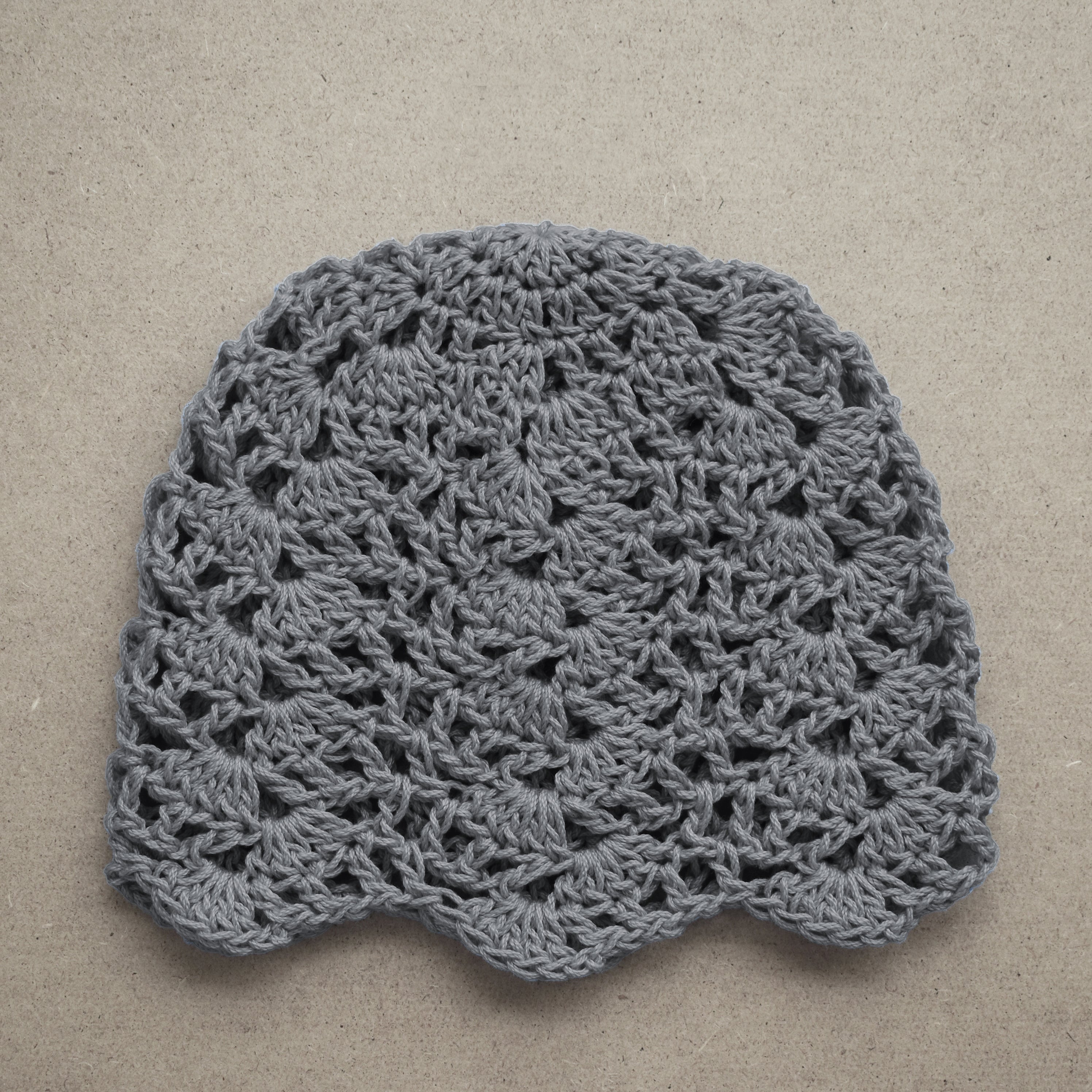 Gray crocheted hat on a beige background.