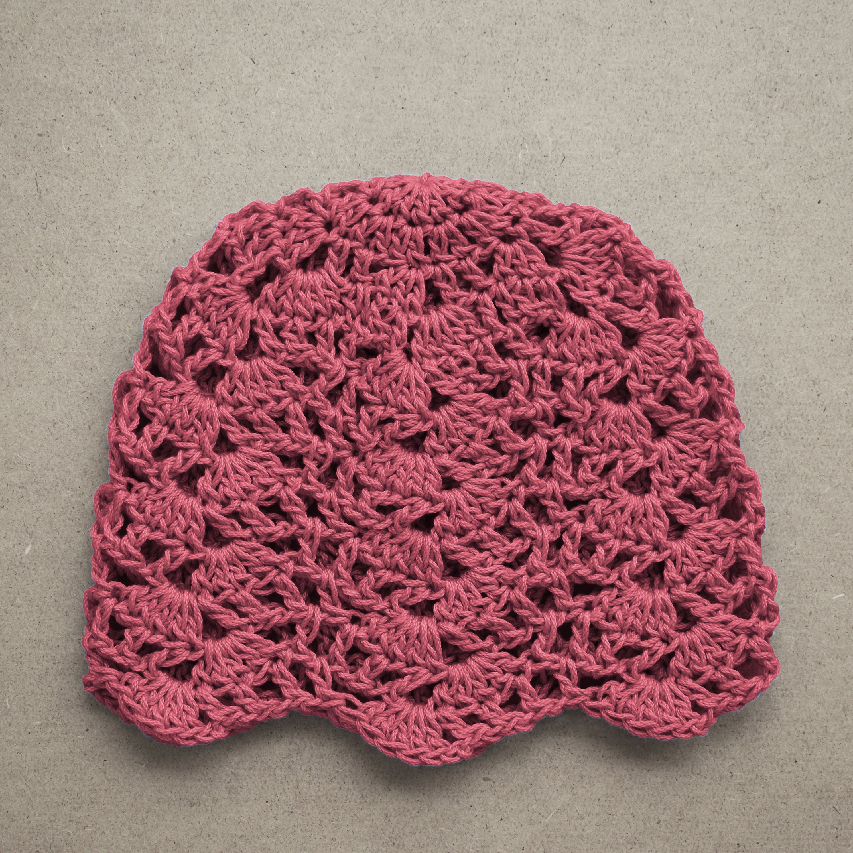 Earthy pink crocheted hat on a beige background.