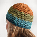 Person wearing a multicolor beanie against a nuetral colored background.