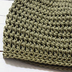Close-up of a green crochet hat on a white background.