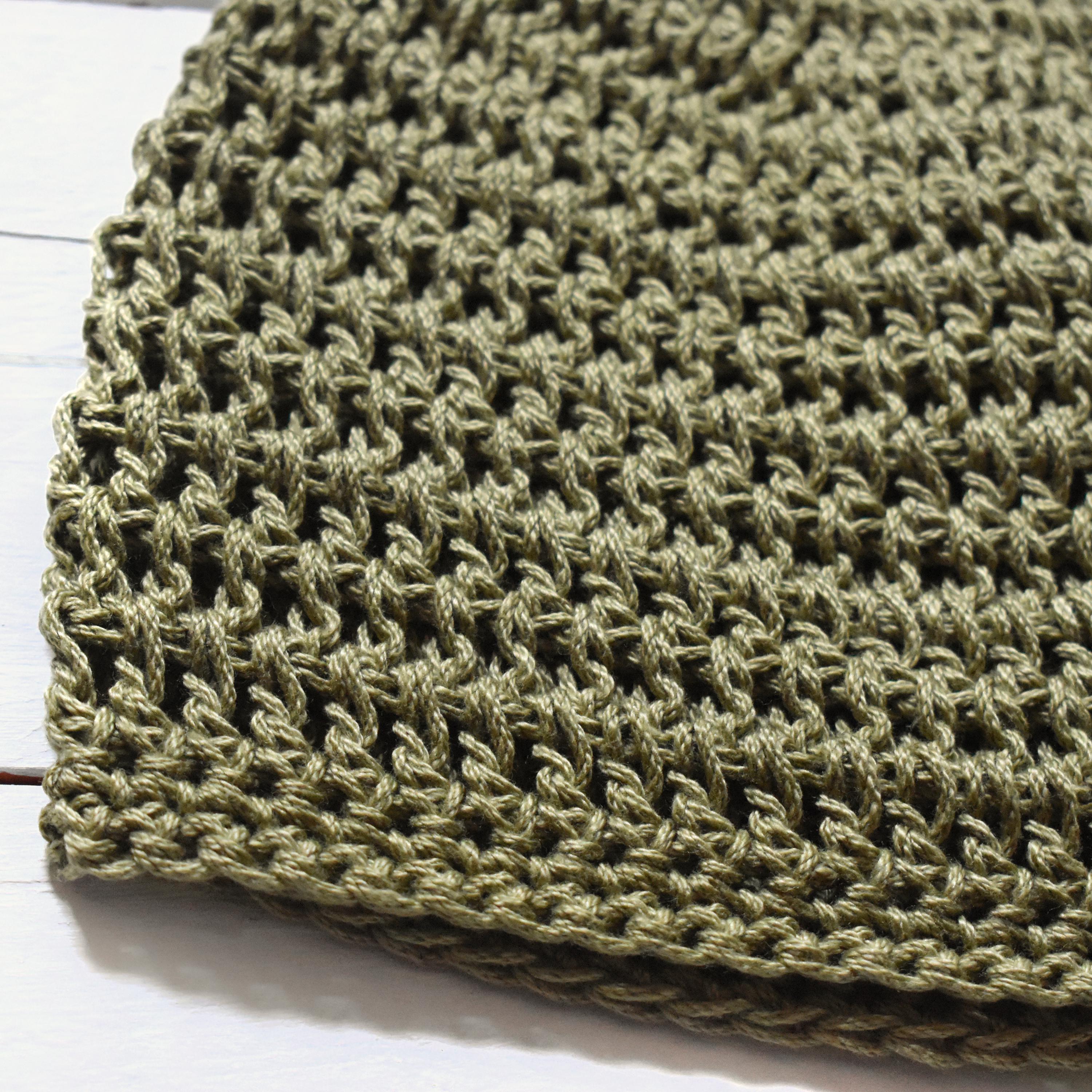 Close-up of a green crochet hat on a white background.