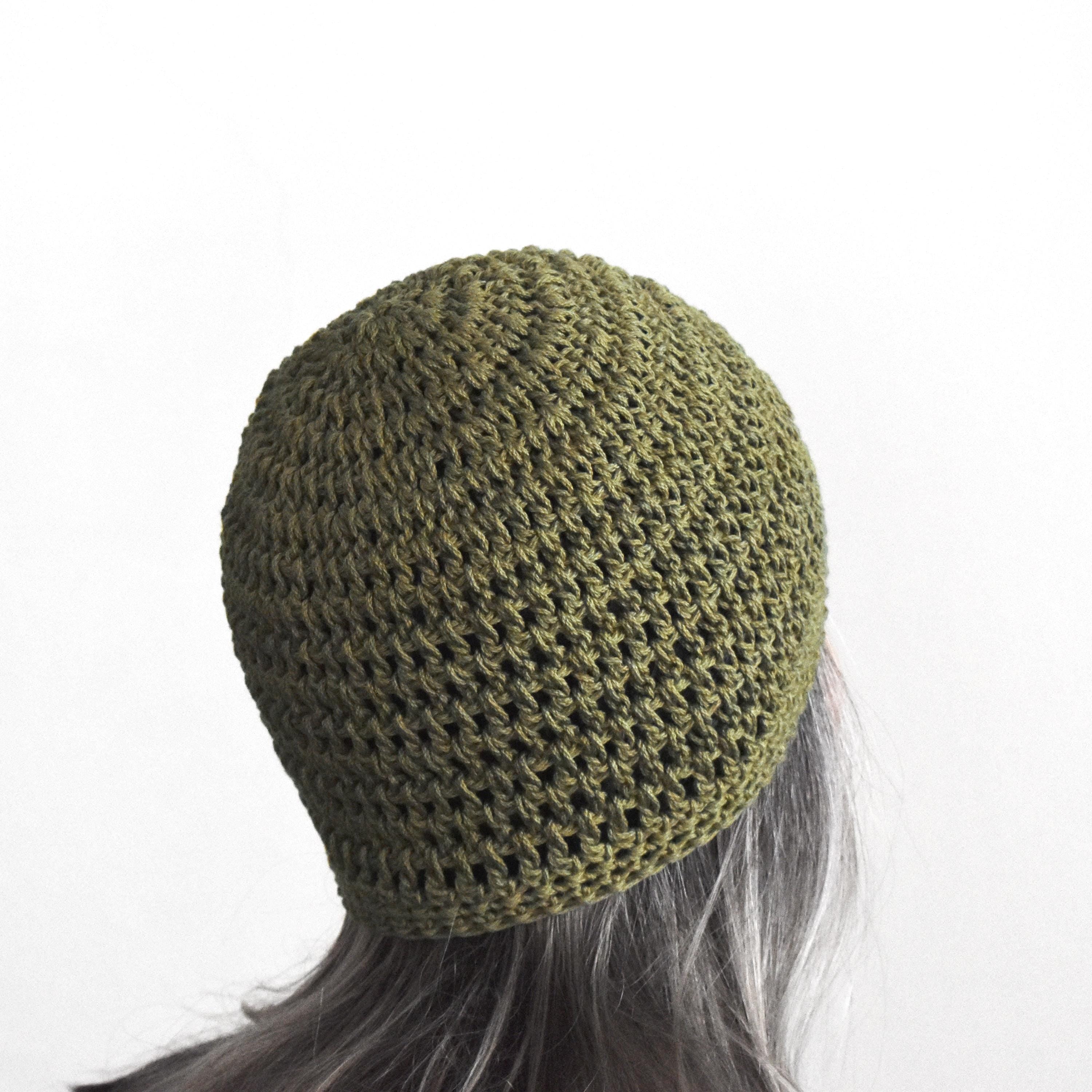Green knitted beanie on a person with gray hair against a white background.