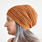 Person wearing a brown knitted beanie against a plain background.