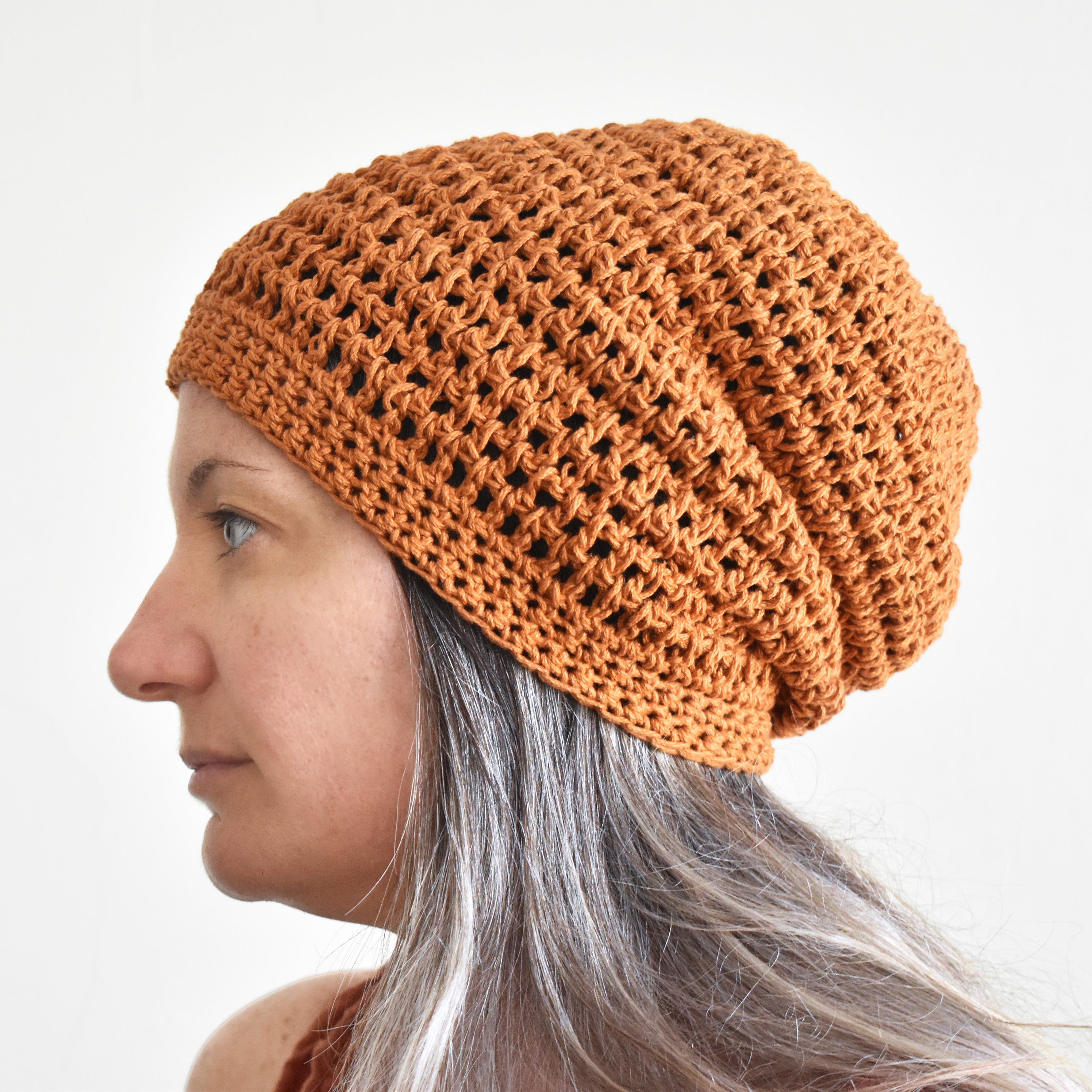 Person wearing a brown knitted beanie against a plain background.