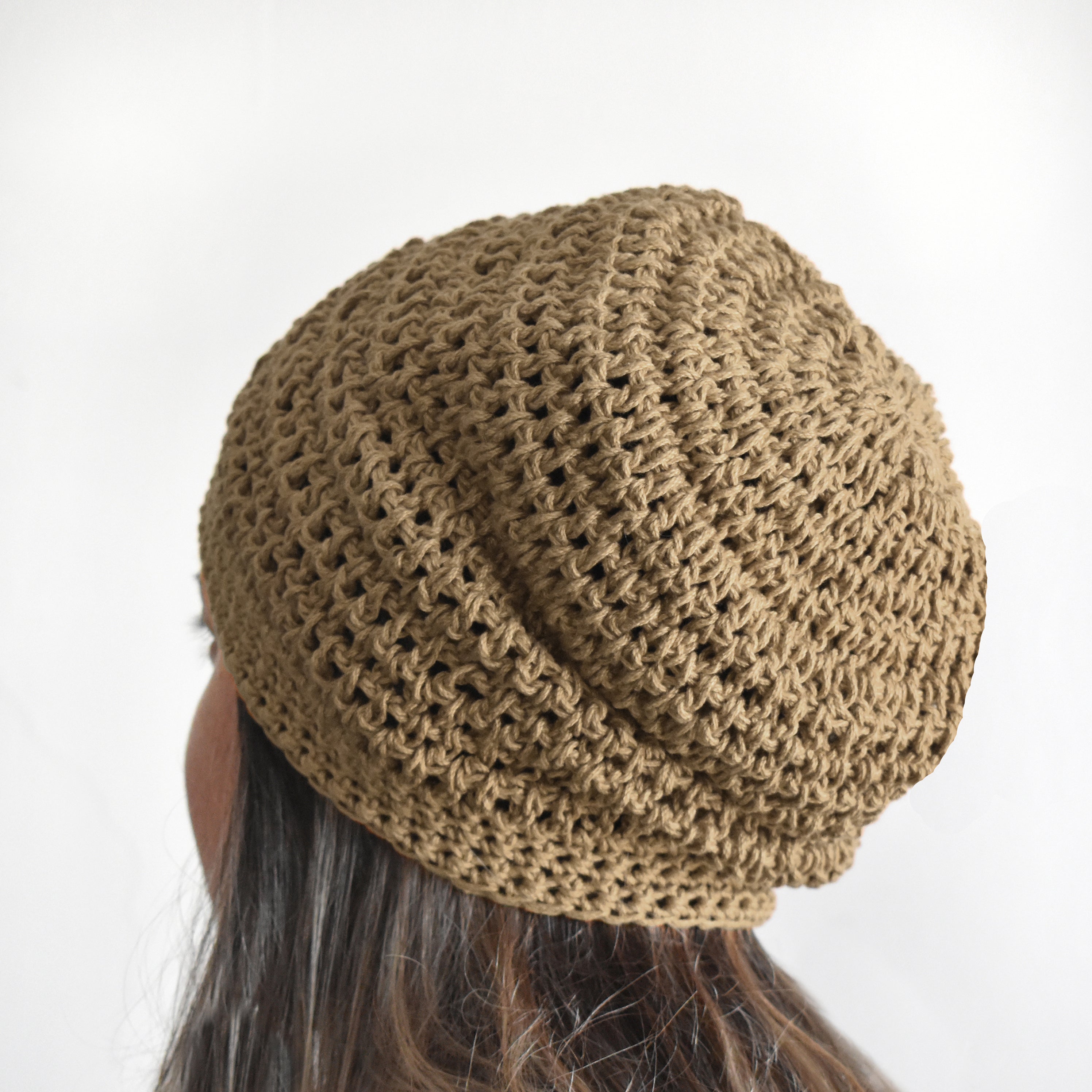 Brown knitted beanie worn by a person on a white background.