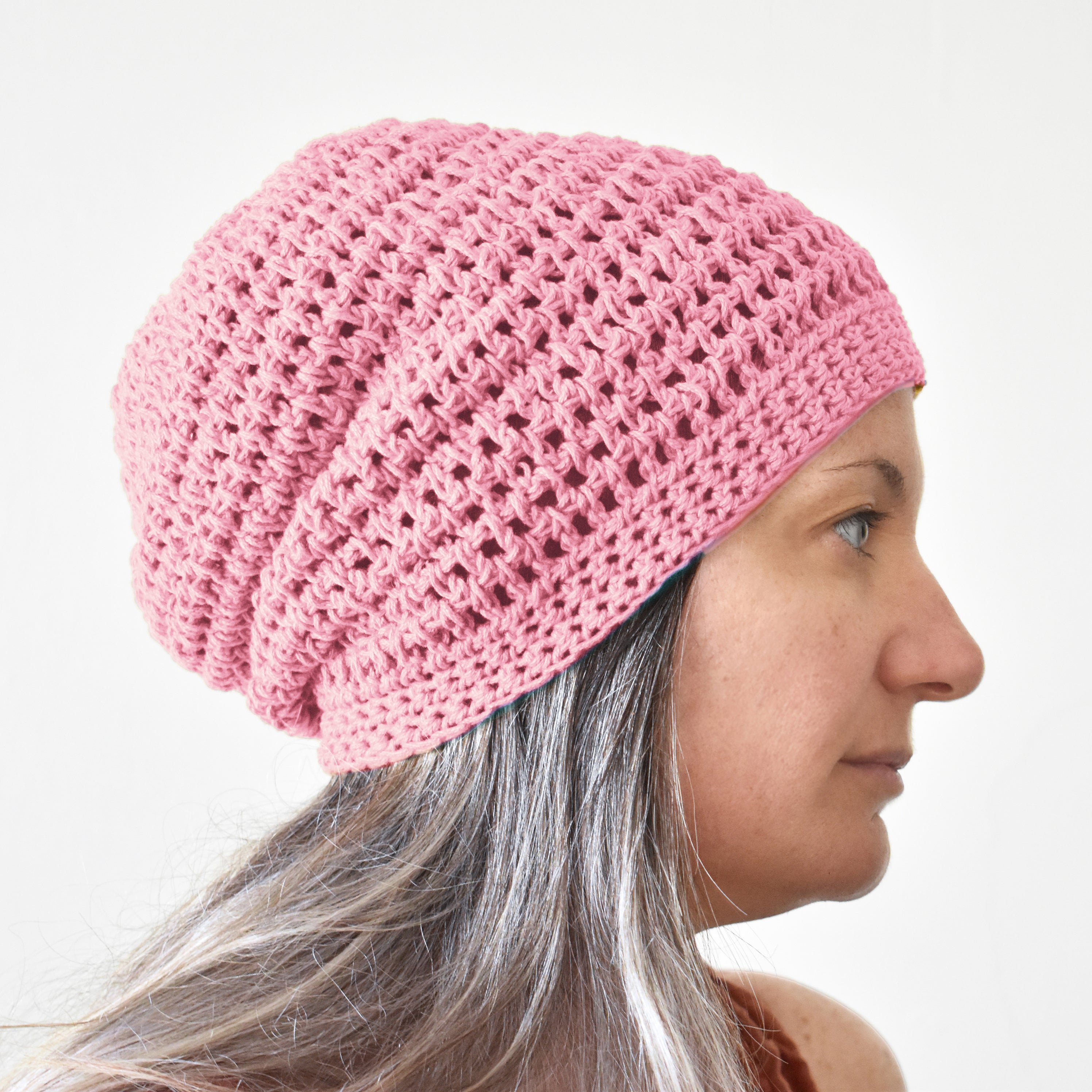 Person wearing a pink knitted beanie against a white background.