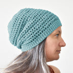 Woman wearing a light blue knitted beanie against a white background.
