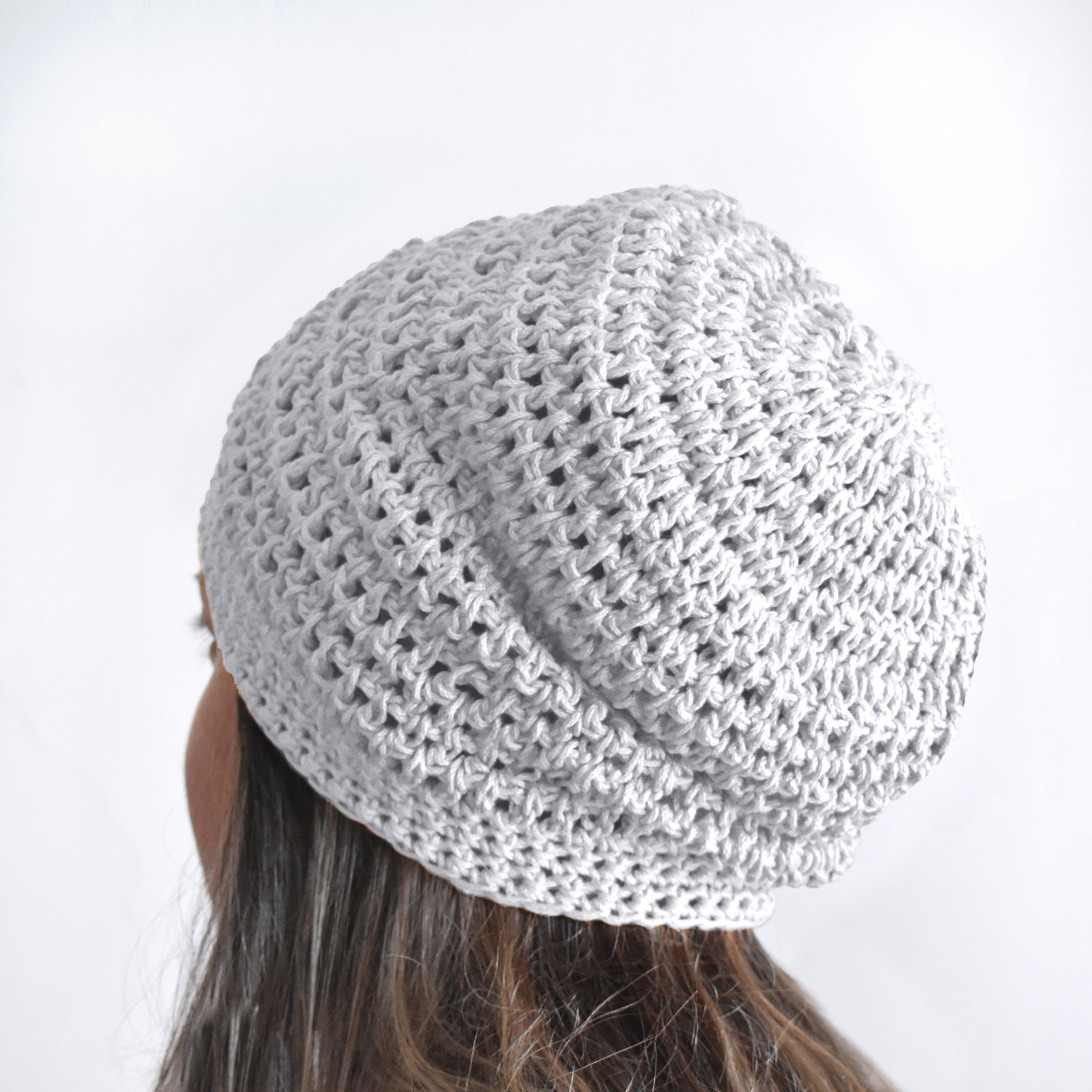 White knitted beret worn by a person on a white background.