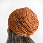 Orange knitted beanie on a person against a white background.